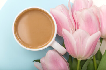 Fototapeta na wymiar CLose up of coffee cup and tulips on blue pastel background