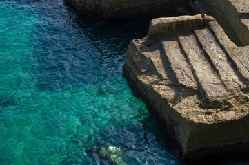 Stairs to the water, old waterfront below Sliema, Malta island. Beautiful blue mediterranean sea. Selective focus.