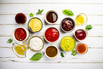 Set of different bowls of various dip sauces on white background, top view