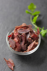 Bowl with jerky meat on a dark background
