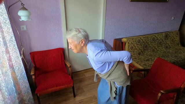 Elderly senior 75s woman with painful feelings massaging low back to reduce ache, backache discomfort. Diseases of older people, sciatic nerve injury concept