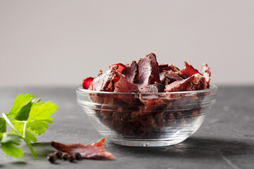 Bowl with jerky meat on a dark background with copy space