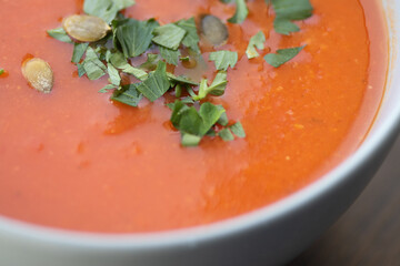 Bowl of red tomato cream soup on wooden table