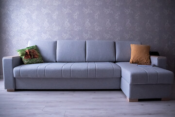 gray corner sofa with pillows on the wall background