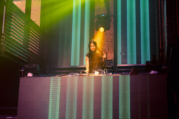 DJ on stage in disco night club mixing techno music beat . Nightlife and dance party .