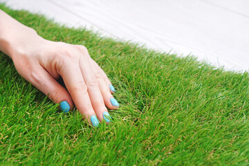 Woman's hand lies on fluffy artificial grass