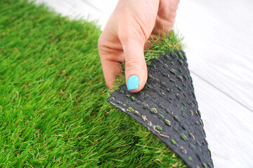 Tender female hand touching an artificial turf roll