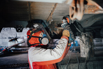 car body work, the master cleans the bottom of the truck with a grinder