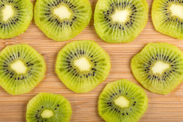 Top view of kiwi slices as texture on wood.