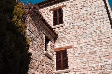 A window with wooden shutters of a medieval brick building (Marche, Italy, Europe)
