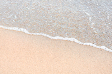 Fototapeta na wymiar Soft sea wave running on sandy seashore. Selective focus, copy space