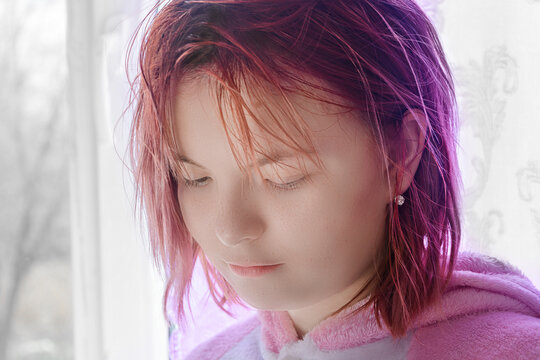 Portrait of teenage girl with red hair. Lady lowers her eyes and looks down. Sad emotions on face. Close-up, selective focus