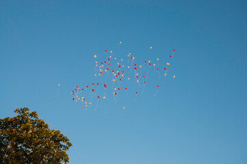 große Anzahl an roten und weißen Luftballons, die in den Himmel steigen,  zum Anlass einer Hochzeit.