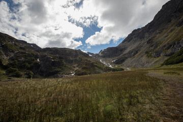 Idyllic hiking landscape. View of the golden meadow and rocky mountains in a summer sunny day. 