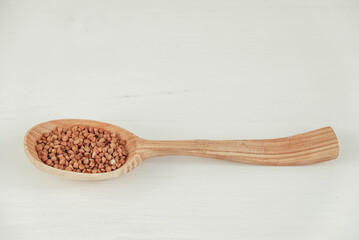 Buckwheat in a wooden spoon on a white background. Copy, empty space for text