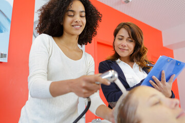 low angle view of trainee haidresser washing customers hair