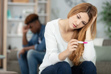 troubled couple holding pregnancy testing kit