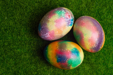 Beautiful multicolored Easter eggs on the grass, top view, flat lay. Easter card.