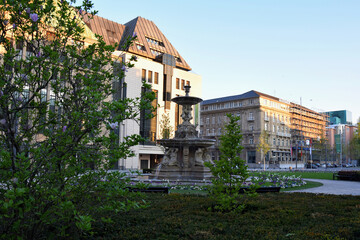 Fountain with figures of people on the background of city buildi