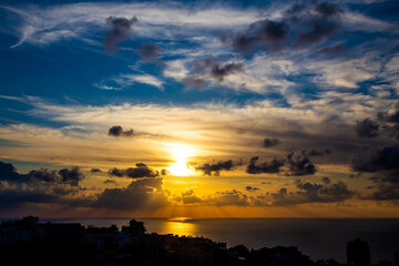 sunset sky with clouds over the sea and the city