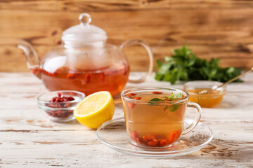Cup and teapot with goji tea on wooden background