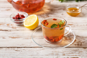 Cup with goji tea on wooden background
