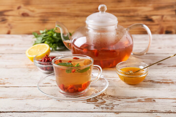 Cup and teapot with goji tea on wooden background