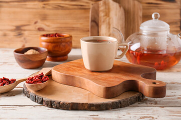 Cup with goji tea on wooden background