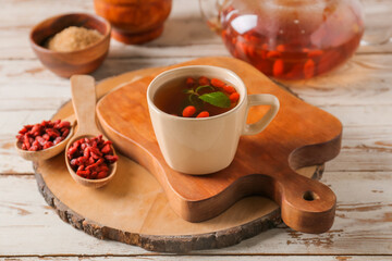 Cup with goji tea on wooden background