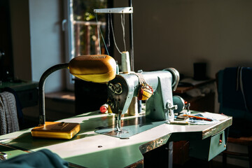 Sewing machine on table in factory in sun light. Small business, fashion designe, Tailor working, candid dressmaker workplace, Clothing or garment industry