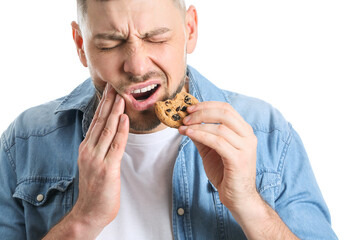Man suffering from pain while eating cookie on white background