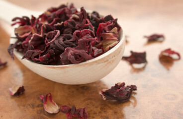 Red tea in a wooden spoon on a wooden background close up