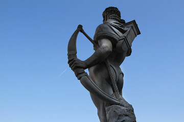 Bust of athlete seen from below and from behind with coffin and arch at Stadio dei Marmi in Rome. Blue sky background