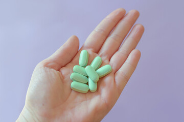 green tablets, vitamins in hand on colorful background. Health care, treatment, cure concept