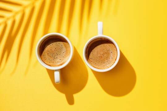 Two White Cup Of Coffee On Yellow Background.