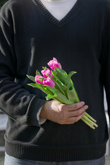 A man holding pink tulips in his hand. Women's Day