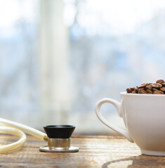 A cup of coffee beans and a stethoscope on an old board in the background of the window. Concept-coffee increases blood pressure, hypertension