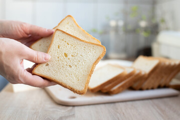 Female hands holding two slices of white bread on the background of the kitchen.
