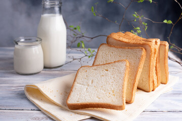 Fresh bread slices with milk bottles on white rustic table with beautiful branch