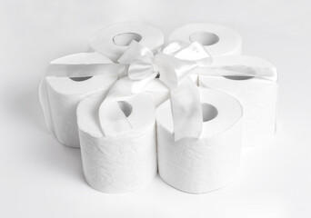 Toilet paper as a gift with a white bow on a white background. White on white.
