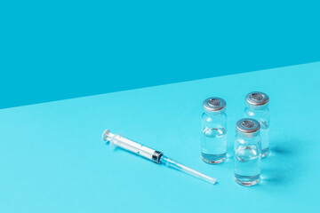 syringes and ampoules with vaccinations on a blue background. vaccination against covid-19. the...