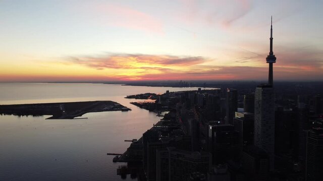 4K aerial flight staright backwards east to west looking at Toronto Skyline at sunset with Billy Bishop in background