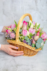 Fototapeta na wymiar Hand holds a festive fruit basket with flowers, tulips. Concept, congratulations on the holiday, birthday, anniversary.