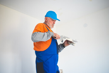 Painter,preparing the wall for painting while standing on ladder