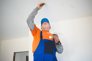Painter,preparing the wall for painting while standing on ladder