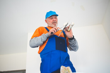 Painter,preparing the wall for painting while standing on ladder