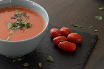 Bowl of red tomato cream soup on wooden table