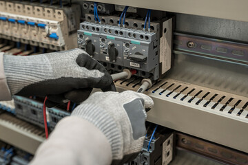 Electricians hands testing current electric in control panel