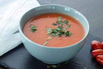 Bowl of red tomato cream soup on wooden table