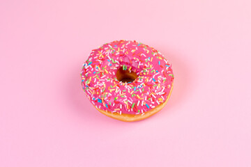 Round doughnut with pink icing close up. Pink background. Copy space. Flat lay